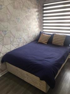 a bed in a bedroom with a tiled wall at Double Room next to Burnham Elizabeth Line Station in Slough