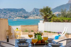 a table with wine glasses and a view of the ocean at Apartamento Casita Blanca - PlusHolidays in Calpe