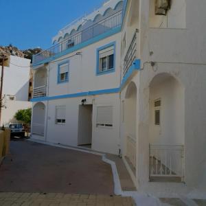 a white and blue building with a parking lot at Rita's Appartements and Studios in Karpathos