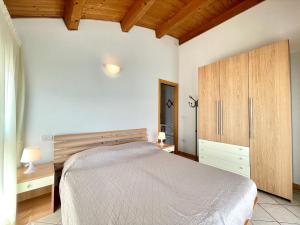 Schlafzimmer mit einem Bett und einem Holzschrank in der Unterkunft Diani Beach - Carraro Immobiliare Jesolo - Family Apartments in Lido di Jesolo