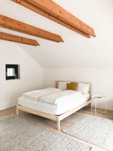 Bett in einem weißen Zimmer mit Holzdecken in der Unterkunft ENTZÜCKENDES GÄSTESTÖCKL am Linzer Pöstlingberg in Linz