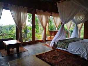 a bedroom with a canopy bed and a window at Villa Rimba Ubud in Tegalalang