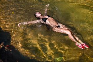 a woman laying in the water in the water at Paraíso Escondido Cabañas, Reserva Rio Claro, San Luis-Doradal in San Luis