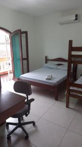 a bedroom with a bed and a chair and a desk at Ombak Guest House in Ubatuba
