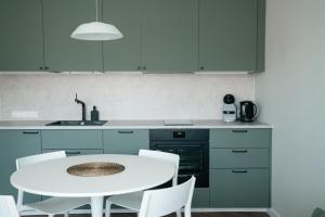 a kitchen with a white table and white chairs at Grey Green Cozy Apartment in Birštonas