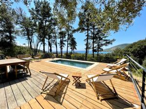 サゴーヌにあるVilla piscine Sagone Paradise avec magnifique vue merのデッキ(テーブル、椅子付)、プールが備わります。