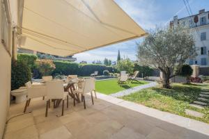 eine Terrasse mit einem Sonnenschirm, einem Tisch und Stühlen in der Unterkunft House with heated swimming pool in Cannes