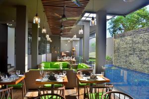 um restaurante com mesas de madeira e cadeiras verdes em Belmont Boutique Hotel em Negombo