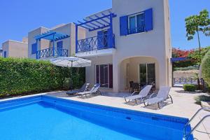 a house with a swimming pool with chairs and an umbrella at Villa Irina Polis in Polis Chrysochous