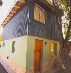 a house with a black roof and a red door at CABAÑA LA SUREÑA in San Martín de los Andes