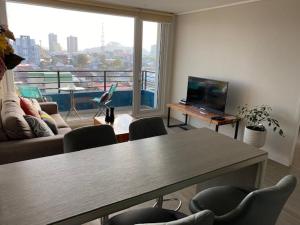 un soggiorno con tavolo, sedie e una grande finestra di Departamento Amoblado con excelente ubicación a Concepción