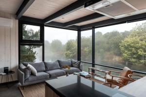 a living room with a couch and large windows at Cabañas Foráneo in Puerto Varas