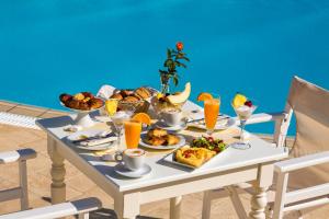 una mesa con alimentos para el desayuno y zumo de naranja en ella en Hotel Odysseus en Chora Folegandros