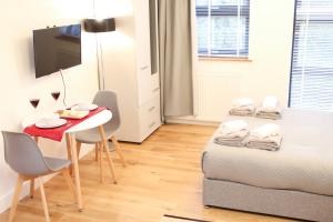 Habitación pequeña con cama, mesa y TV. en Executive Bright and Airy Studio Apartment in Sydenham, en Londres