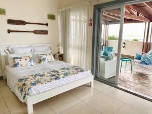a bedroom with a bed and a sliding glass door at Hibiscus Penthouse vue mer 2 chambres in Trou aux Biches