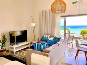 una sala de estar con sofá y TV y el océano en Hibiscus Penthouse vue mer 2 chambres, en Trou aux Biches