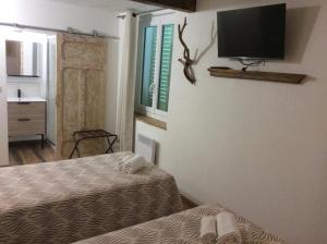 a room with two beds and a tv on the wall at Hotel Restaurant de la Poste in Aullène