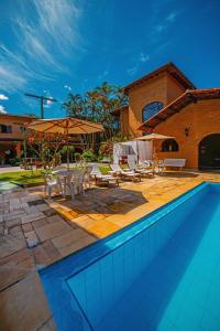 einen Pool mit Stühlen und Tischen sowie ein Gebäude in der Unterkunft Giprita Wellness Hotel Ubatuba in Ubatuba