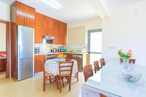 een keuken met een tafel met stoelen en een koelkast bij Villa Styliani in Droushia