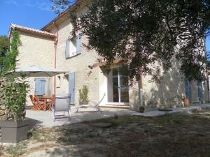 a house with a patio with a table and an umbrella at Le Mas des Meras - Gite Côté mas in Lurs