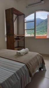 a bedroom with a bed with a large window at Ombak Guest House in Ubatuba