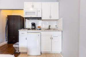 a white kitchen with a sink and a microwave at The Central Park North in New York