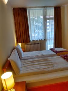 a bedroom with a large bed with two windows at Kolimechkov Apartments Borovets in Borovets