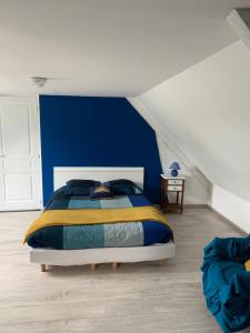een slaapkamer met een bed met een blauwe muur bij Le Mesnil Normand in Fort-Moville