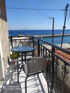 una mesa y una silla en un balcón con vistas al océano en Despoina SEASIDE APARTMENT AGIOS KONSTANTINOS SAMOS en Ágios Konstantínos