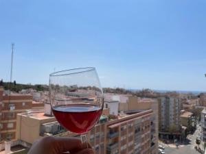 eine Person, die ein Glas Wein vor einer Stadt hält in der Unterkunft Unik Vacation Rovira i Virgili in Tarragona