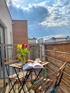 een tafel met bloemen en een boek op een balkon bij BP Apartment in Toruń