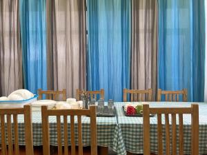a dining table with blue curtains and a table with chairs at The Puma house in Leh