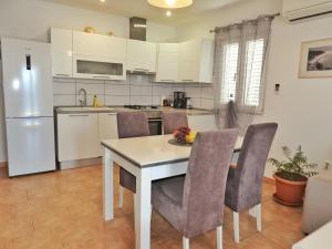 eine Küche mit Tisch, Stühlen und Kühlschrank in der Unterkunft Apartmani Robert in Bol