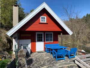a red and white shed with blue tables and chairs at Hytte ved sjøen in Kristiansand