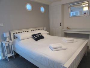 ein Schlafzimmer mit einem großen weißen Bett mit Handtüchern darauf in der Unterkunft The Cuddy - Apartment with garden in Brixham