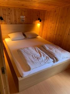 Cama en habitación con paredes de madera en Hytte ved sjøen en Kristiansand