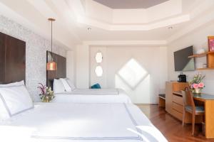 ein weißes Schlafzimmer mit zwei Betten und einem Schreibtisch in der Unterkunft Santa Rita Hotel del Arte in Zacatecas