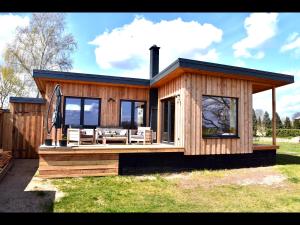 Una pequeña casa de madera con terraza y sillas. en Ferienhaus M&M, en Schwarz