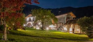 a house with christmas lights in a yard at night at La Roggia - Historic Molino Maufet Watermill - Lake Como in Colico