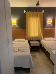 um quarto de hotel com duas camas e uma janela em Kılavuz otel em Bodrum City