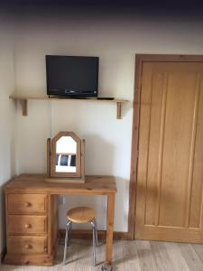 a desk with a mirror and a television on a wall at Darach Brae in Beauly