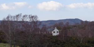 a white house on a hill with mountains in the background at Darach Brae in Beauly