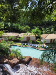 a swimming pool with lounge chairs and a waterfall at Hotel Serra do Gandarela in Rio Acima