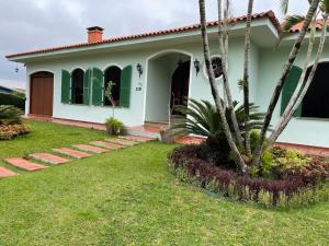una casa blanca con una palmera en el patio en Dom Ravello, en Telêmaco Borba