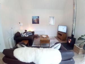 un soggiorno con un divano e una TV di Sawmill Cottage a Grantown on Spey