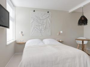 a white bedroom with a bed and a tv at Holiday Home near Dutch Beach and Nature in Oostkapelle
