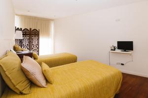 a bedroom with a yellow bed and a television at Casa do Passadiço - Alvarenga in Alvarenga