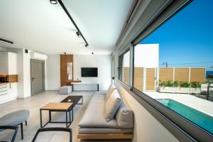 uma sala de estar com uma grande janela e uma piscina em Casa Calma ll em Panormos - Rethymno