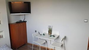 uma mesa branca com cadeiras e uma televisão na parede em Apartament i pokoje u Dany i Piotra Zator Przeciszów em Przeciszów