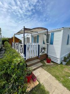 a white house with a porch and a white fence at Sylvie propriétaire du mobil-home " Camping de la Chanterie" in Saint-Pair-sur-Mer